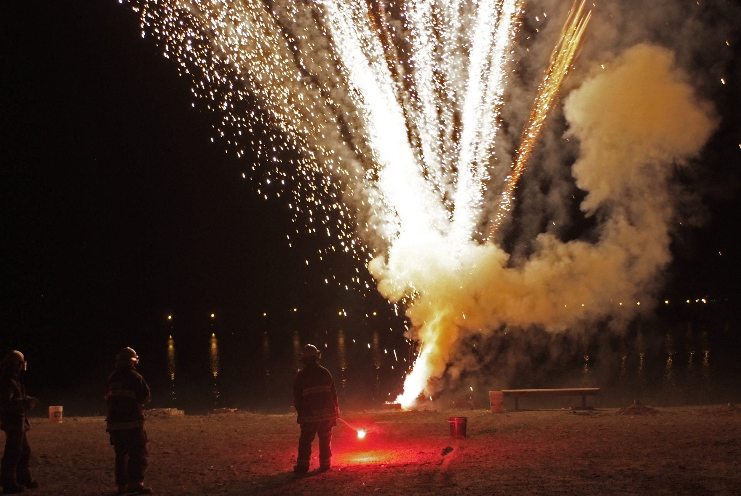 Firemen standing by an exploding firework for the annual firework show.