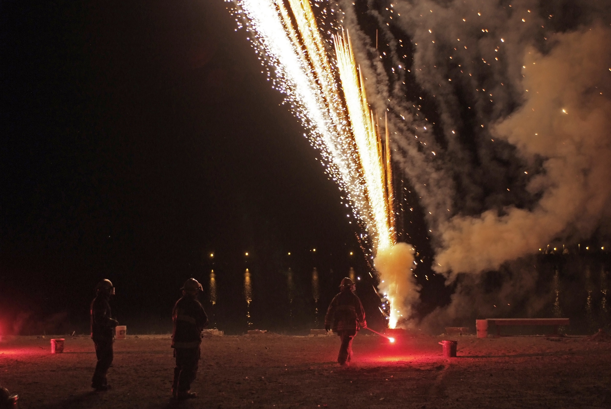 Firemen standing by an exploding firework for the annual firework show.